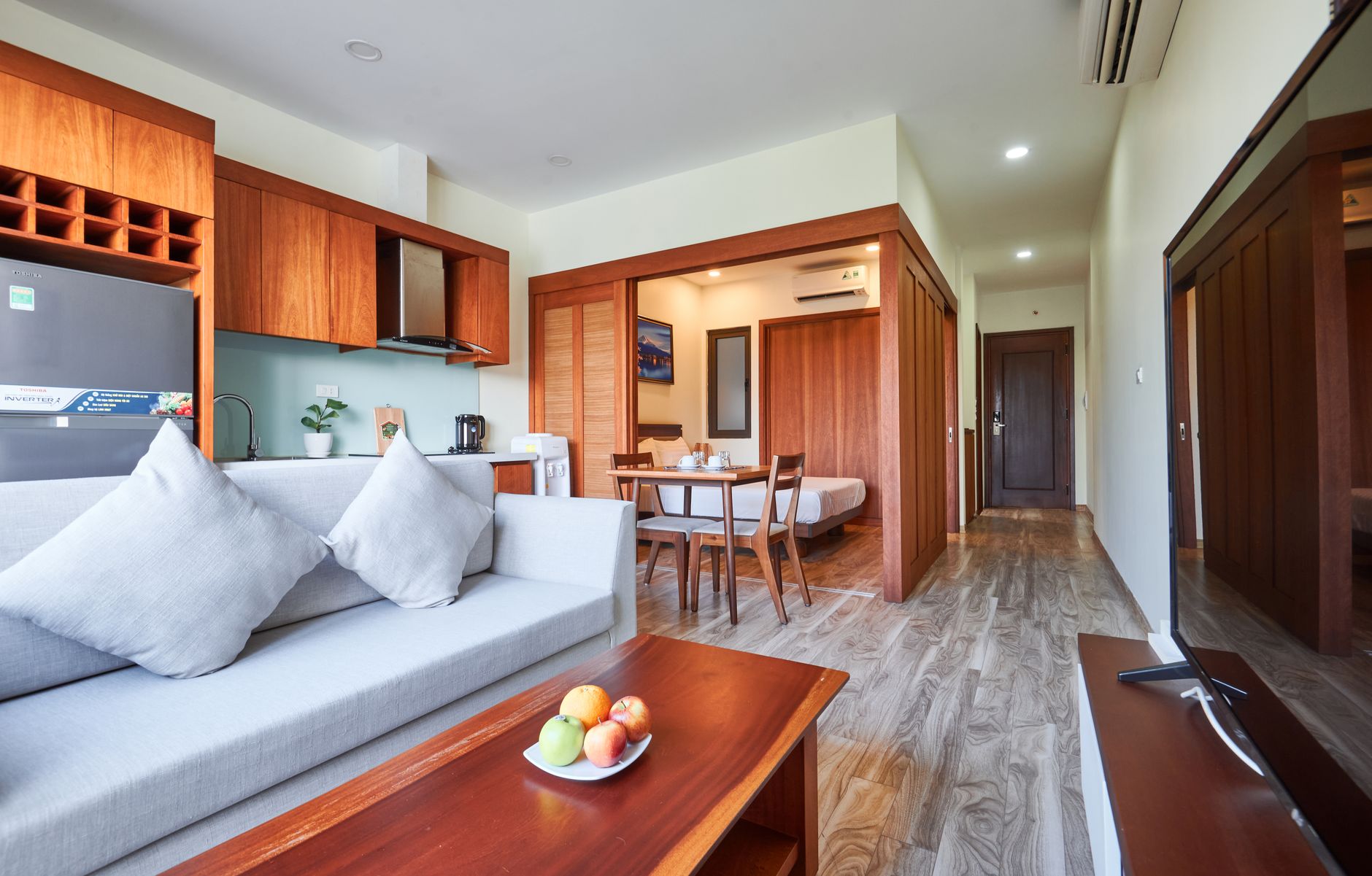 Spacious modern apartment living room with wooden furniture and neutral tones.